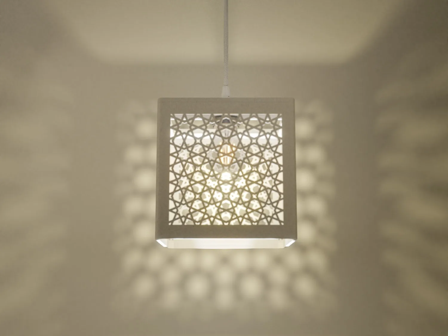 Illuminated Cordoue pendant casting geometric shadows on the wall